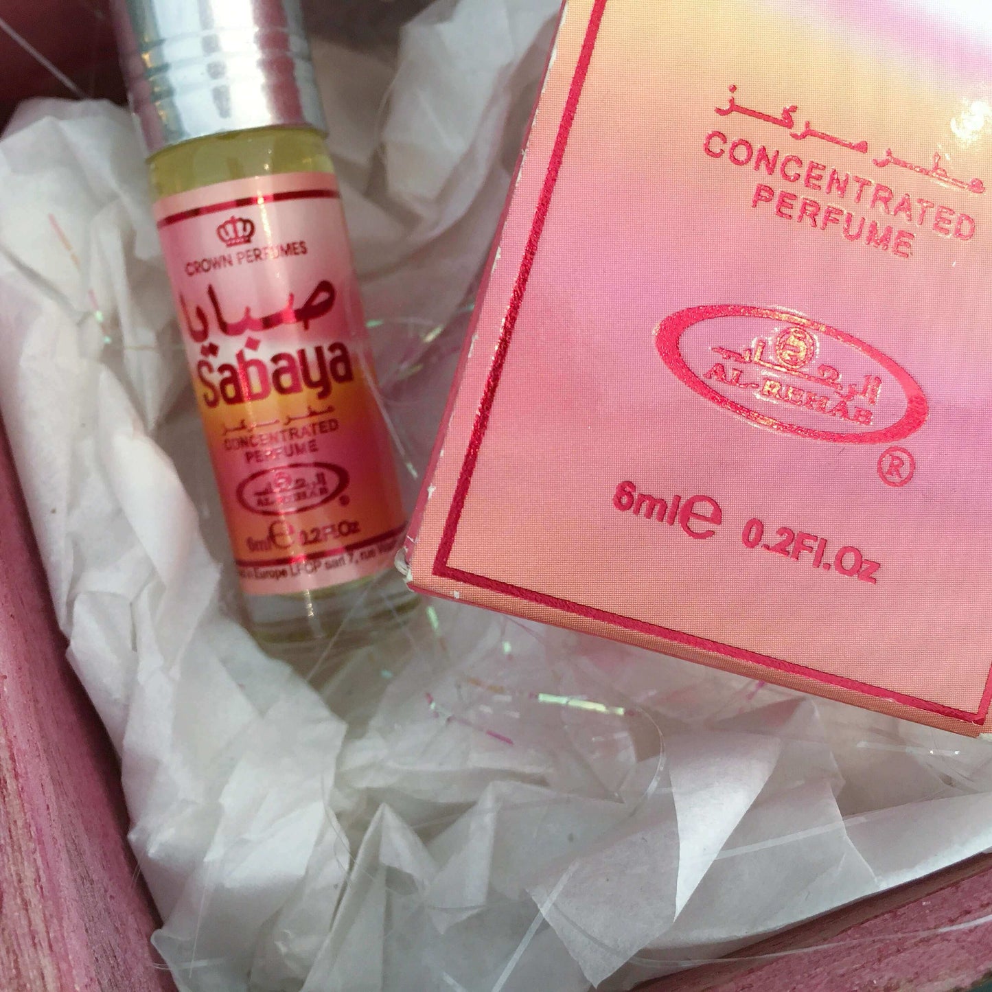 Contents detail view of perfume bottle and its packaging nestling on white tissue paper in the box.