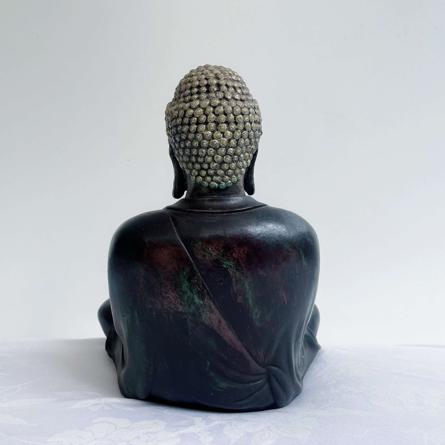 Back view of buddha, smooth painted ebony robes and gold painted head.