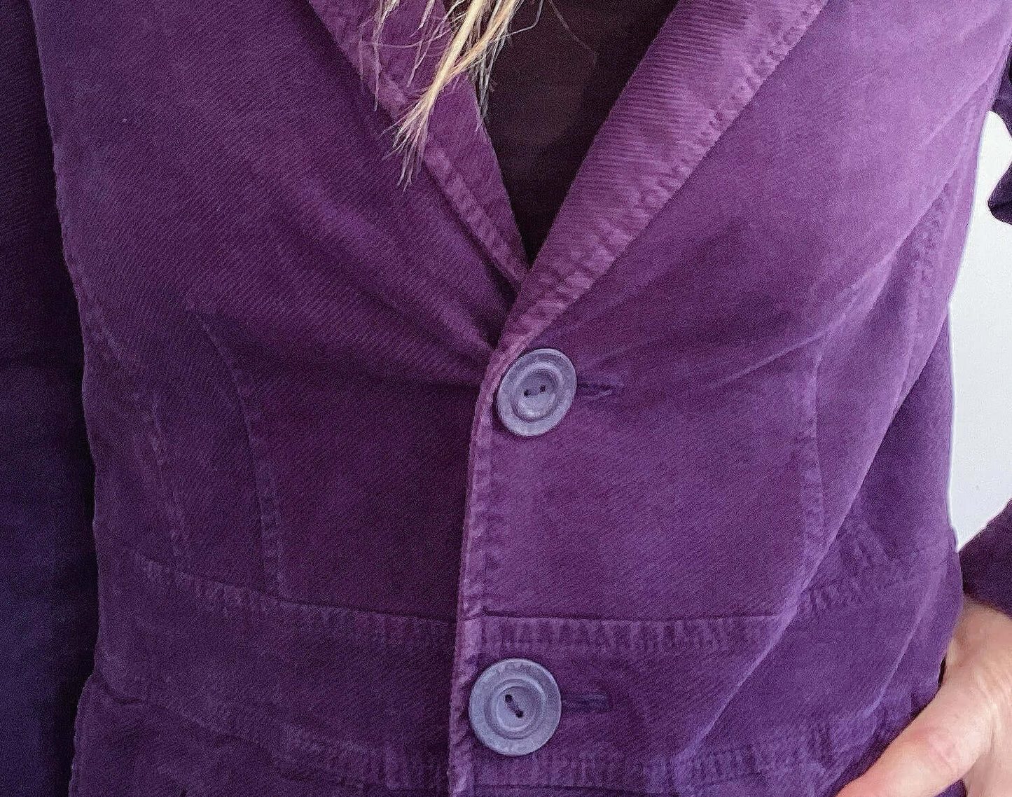 Detail view of dark purple single breasted corduroy blazer and purple buttons.
