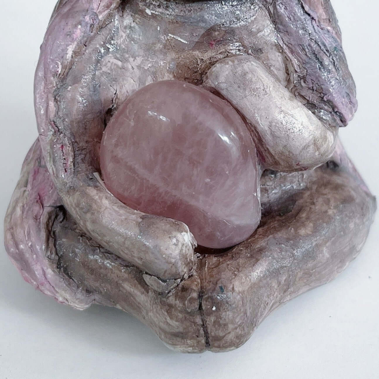 Detail of elemental, brown wash painted figure, jewel band on head, pink wash long hair, holding a tumbled rose quartz.