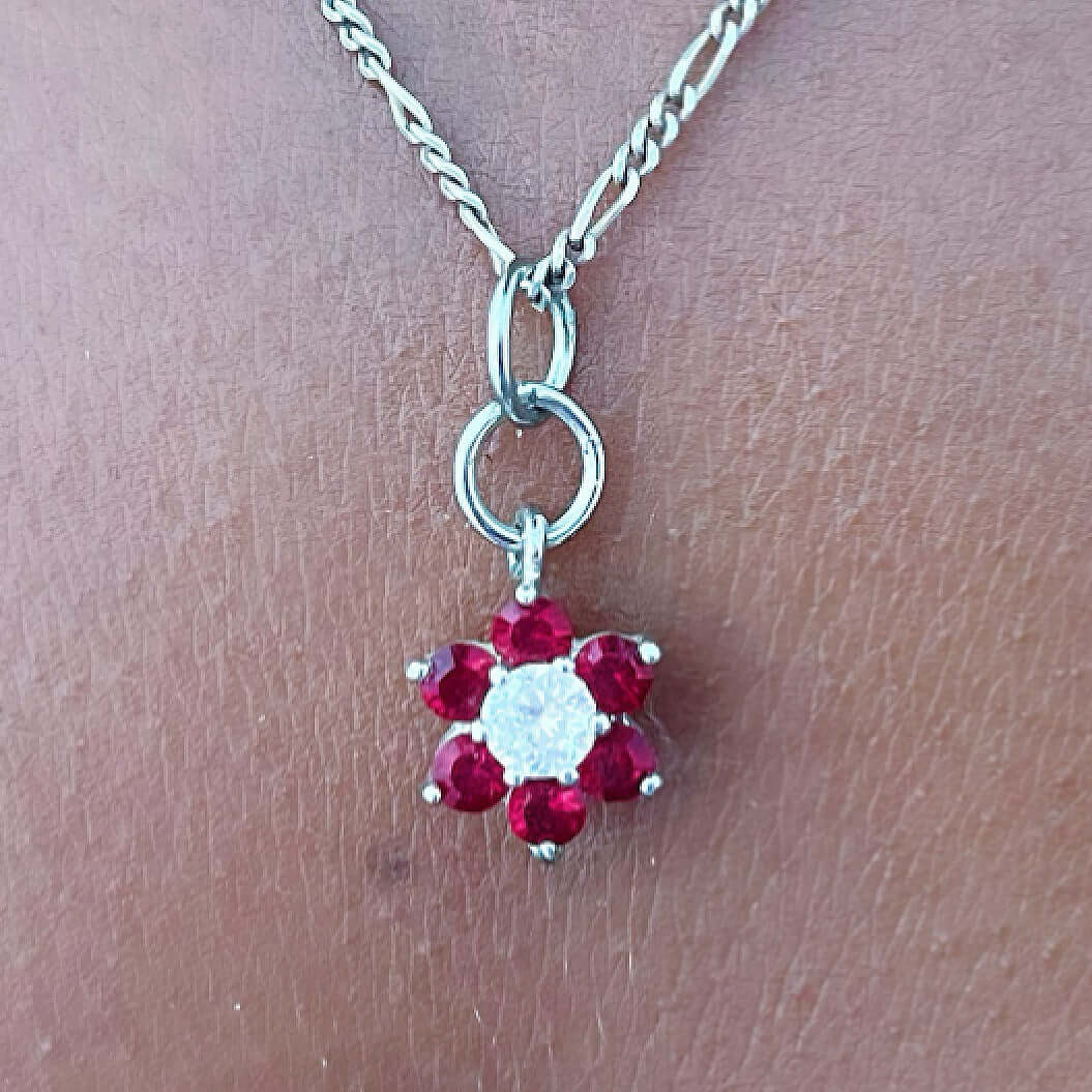 Detail view flower shaped pendant with six garnet petals and a cubic zirconia center.