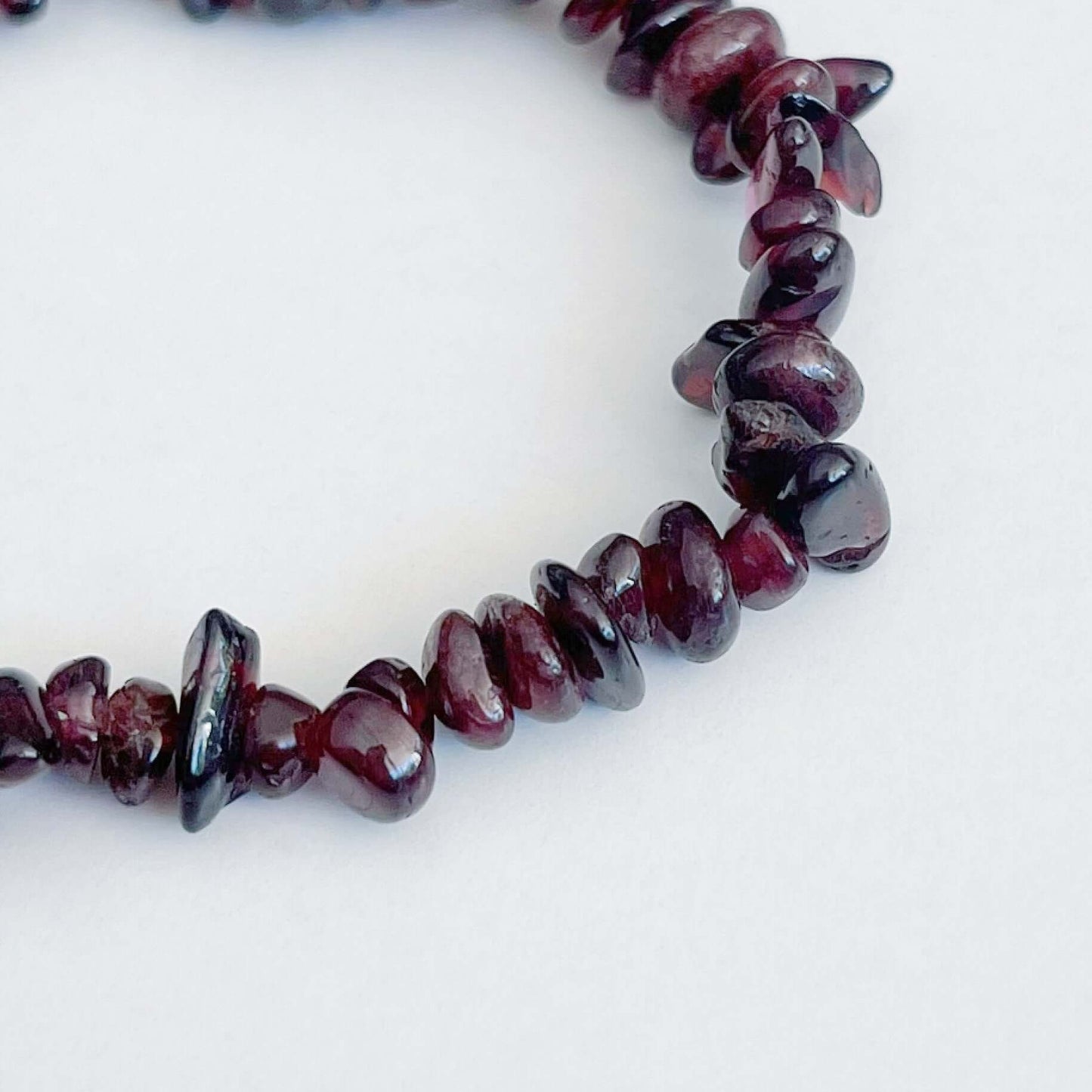Detail view of the tumbled semi-precious stones, shades of deep plum/ruby translucent.