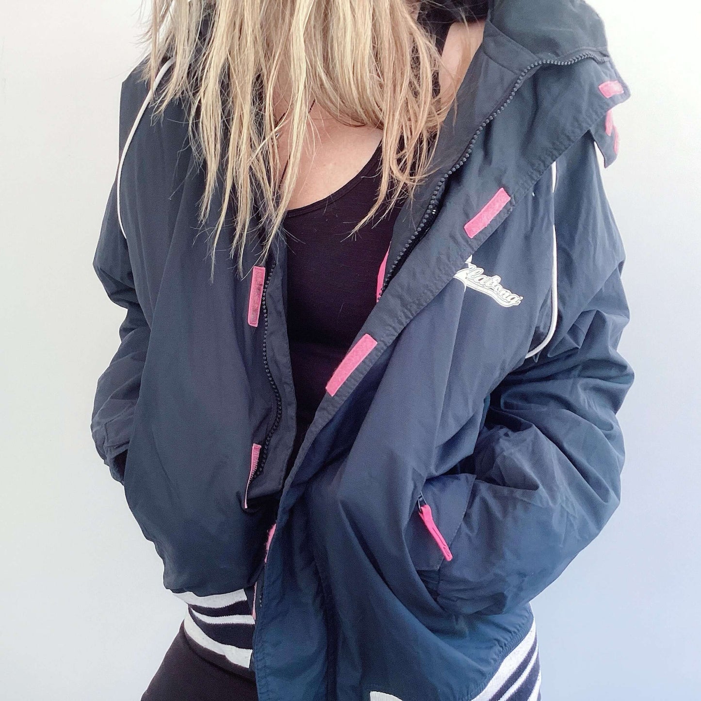 Black jacket with pink lining, black and white striped cuff and hem ribbing, white billabong print on the back.