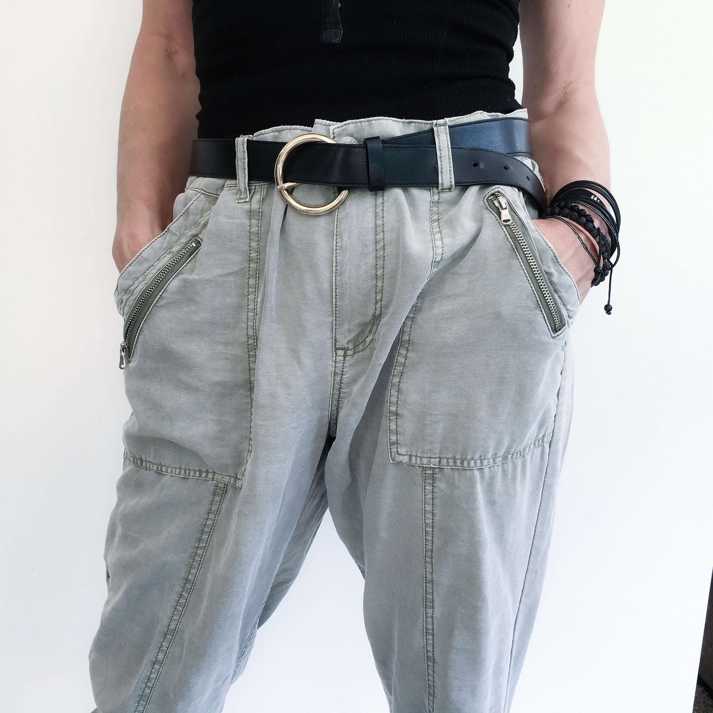 Detail view of pale khaki elasticated pants with belt, side pockets.