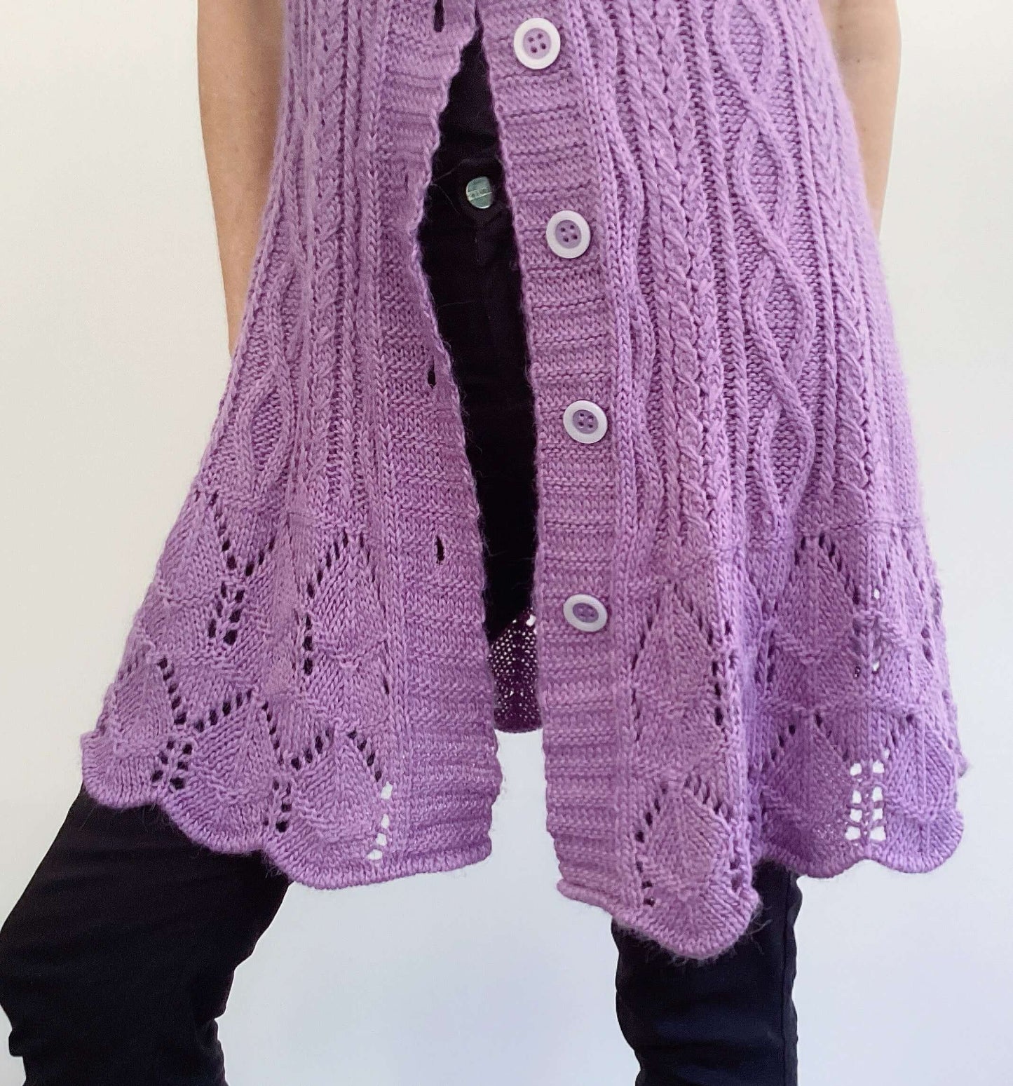 Front detail of purple button up cardigan, celtic cable knit stitches, scalloped at the hem.