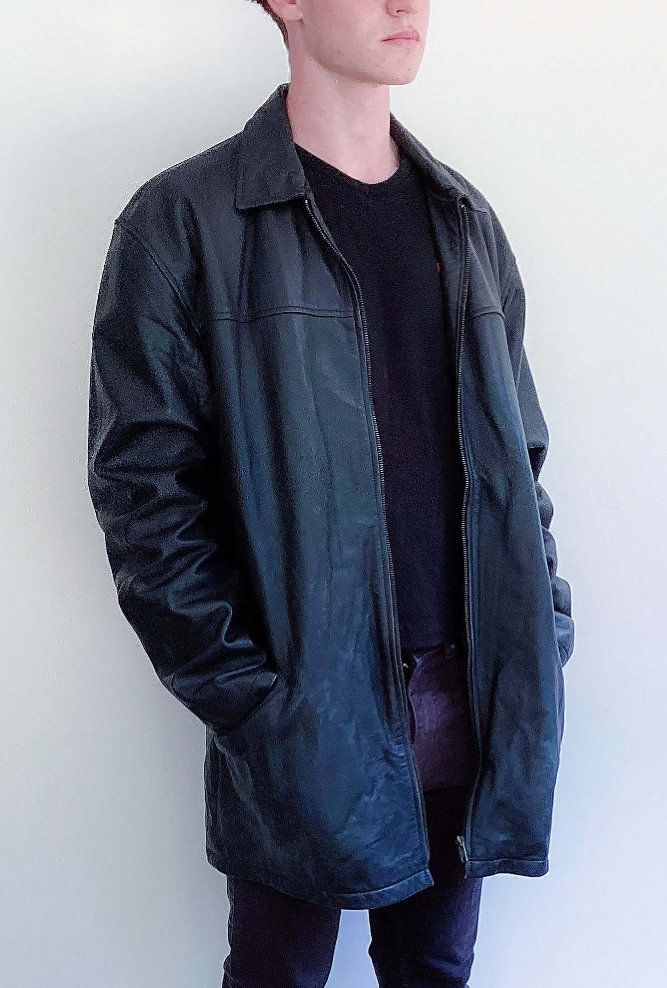 Side view of black leather jacket, mid thigh length, zip up.