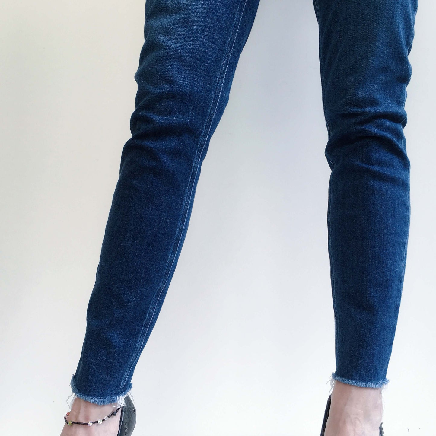 Front detail view uniform color navy blue jeans thigh to ankle.