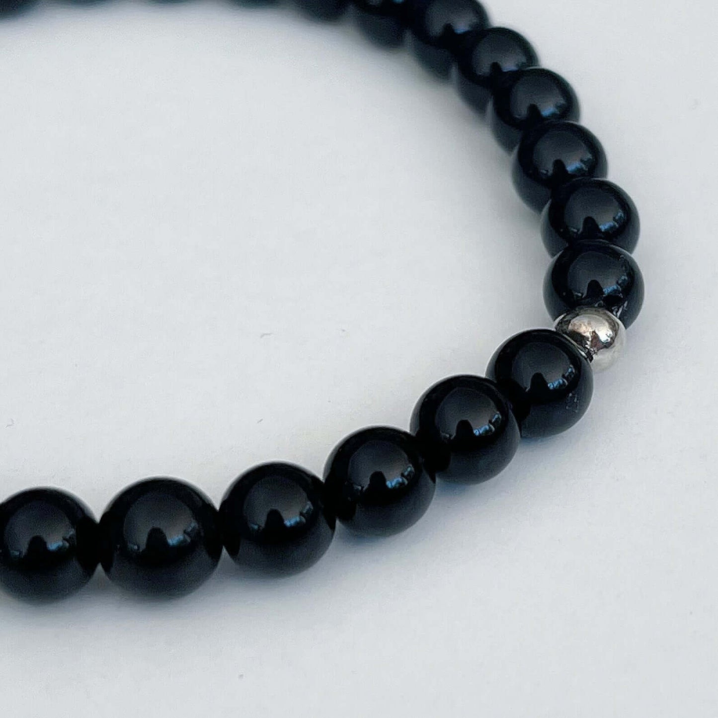 Detail view of elasticated bracelet, showing the individual beads, which have shades of deep green.