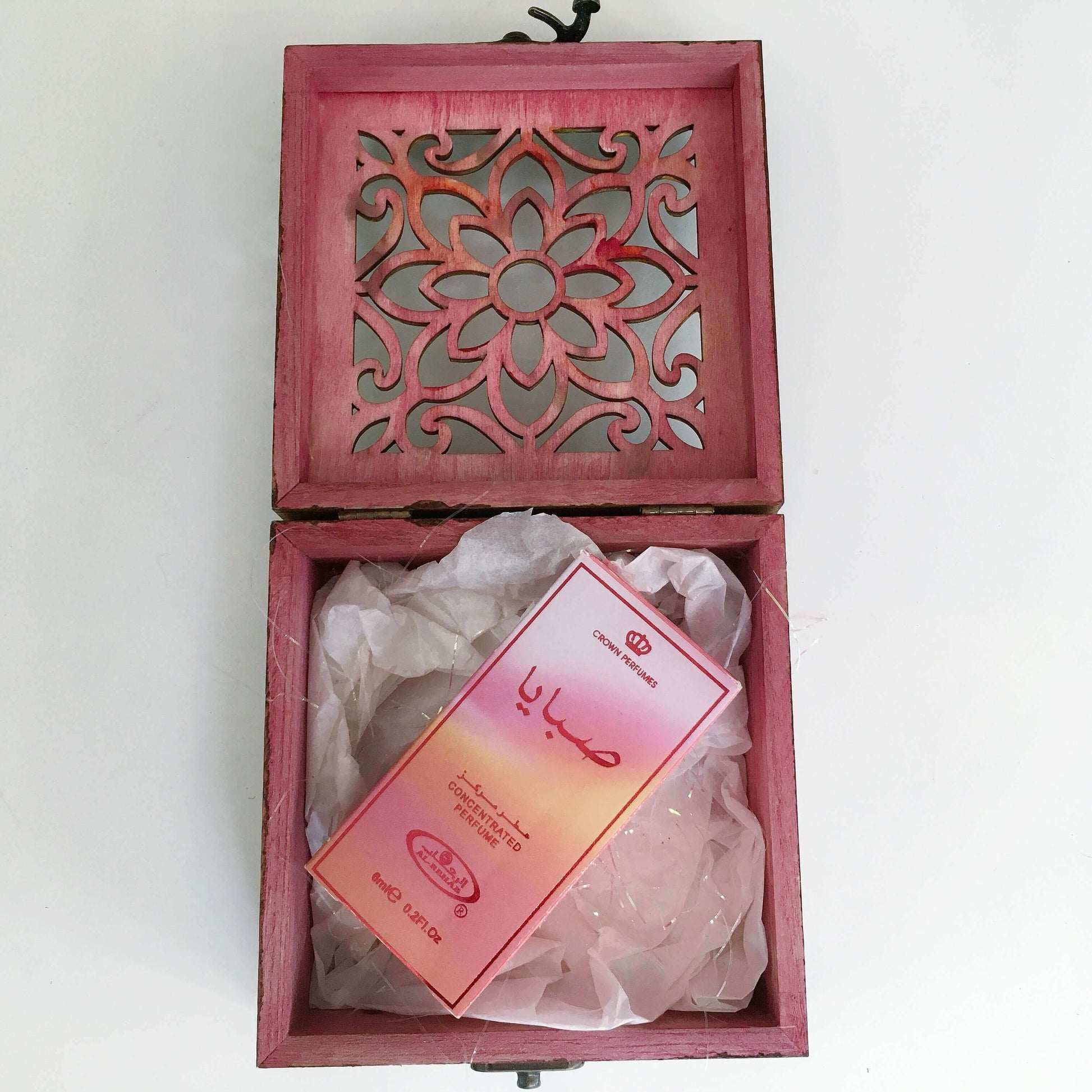 Contents view of perfume bottle inside its packaging nestling on white tissue paper in the box.