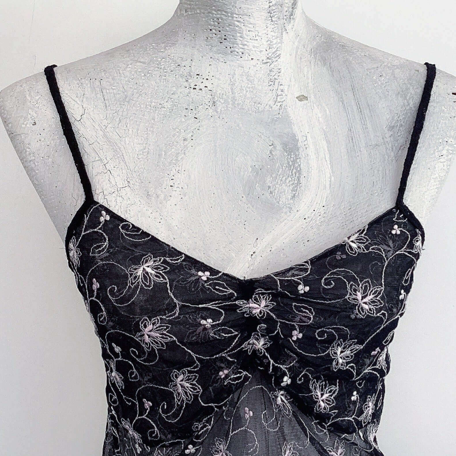 Detail view of black net cami with very pale pink floral embroidery bust area.