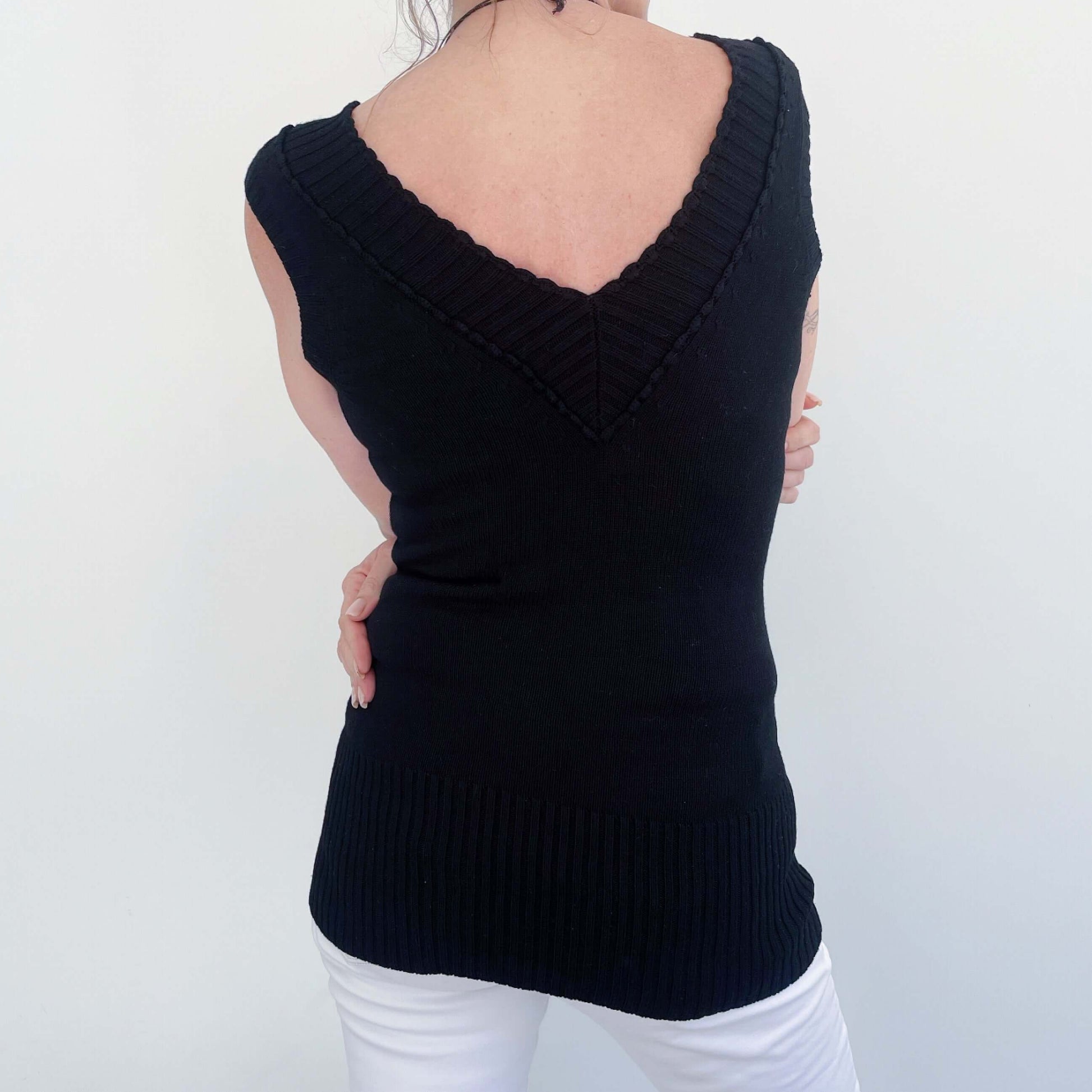 back view of the black knitted jersey, showing the V neck at the back, cropped short sleeve. Wide ribbing on hem.