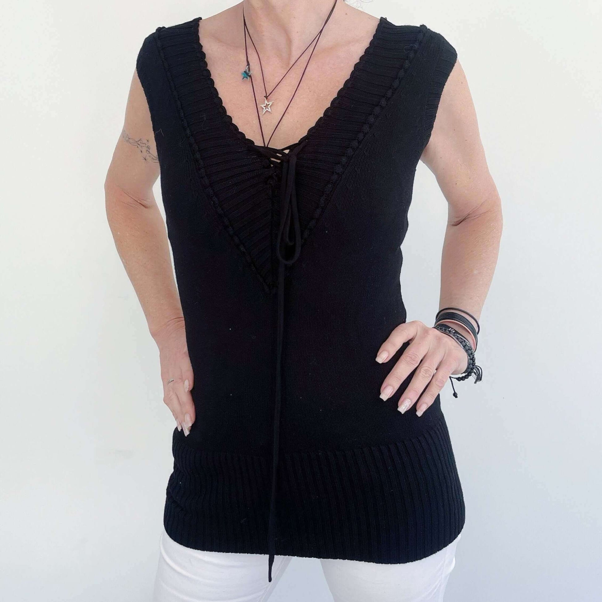 Front view of the black knitted jersey, showing the ribbing and lace up detail. Cropped short sleeve.