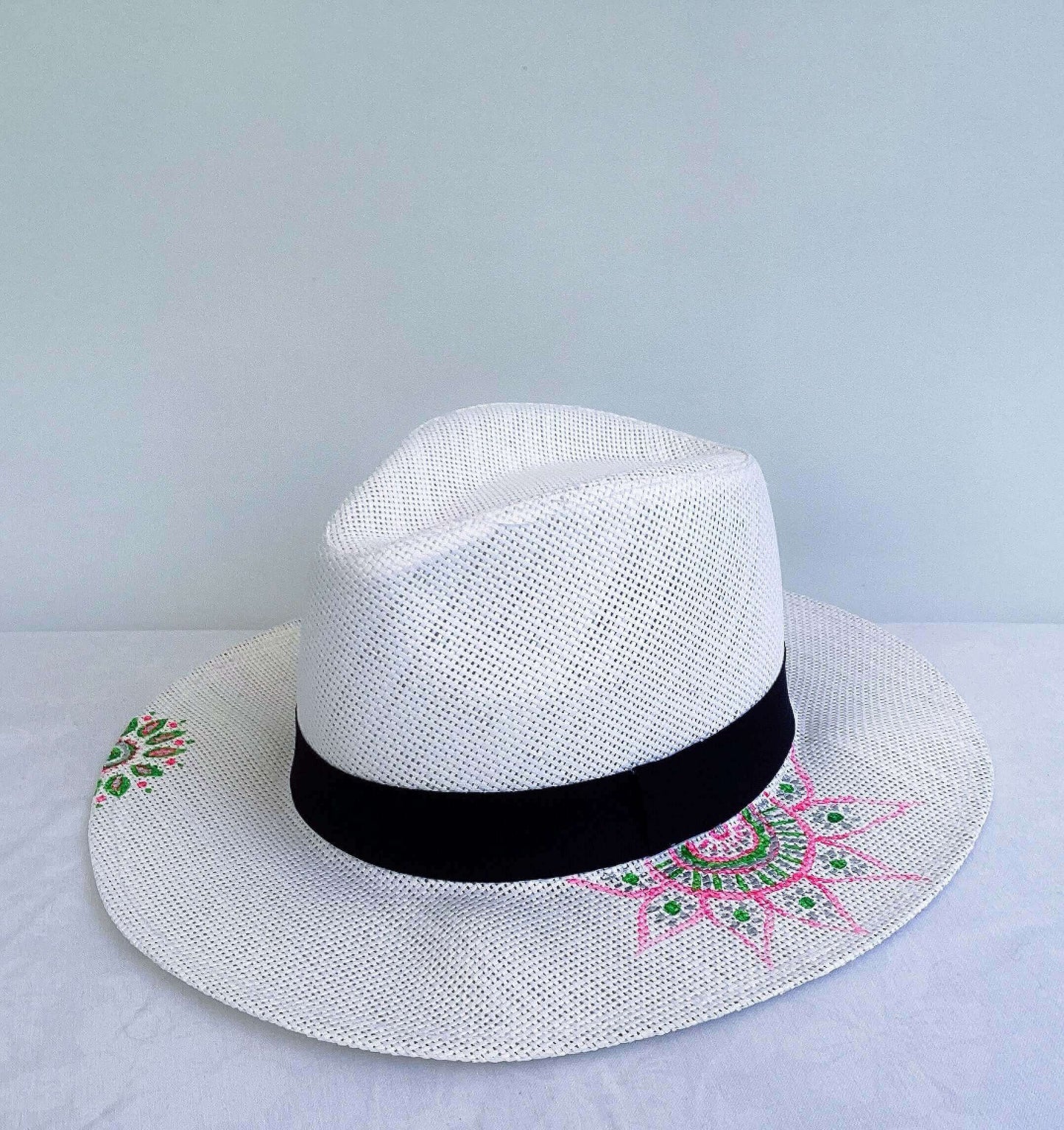  Panama hat, black band at base, with hand painted green and pink mandalas asymmetrically positioned.