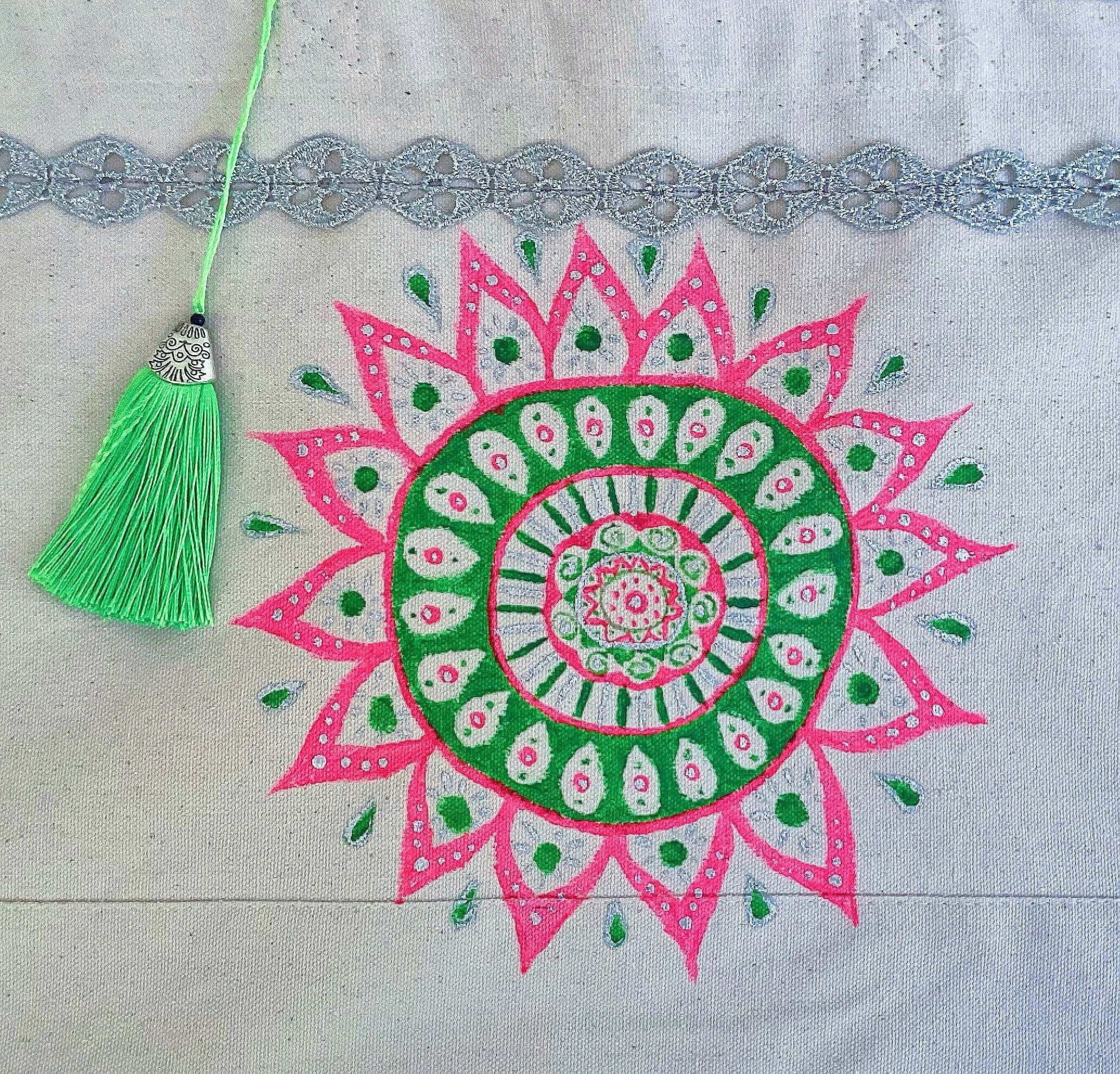 Detail view of canvas tote bag, with large hand painted green and pink mandala, green tassel.