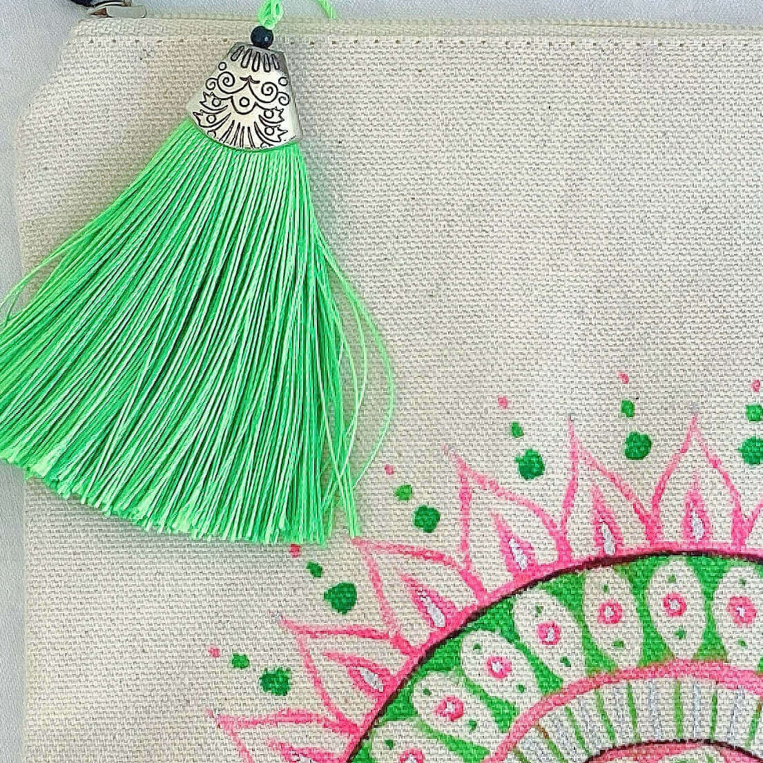 Detail view of canvas make-up pouch, with hand painted green and pink mandala, and green tassel.