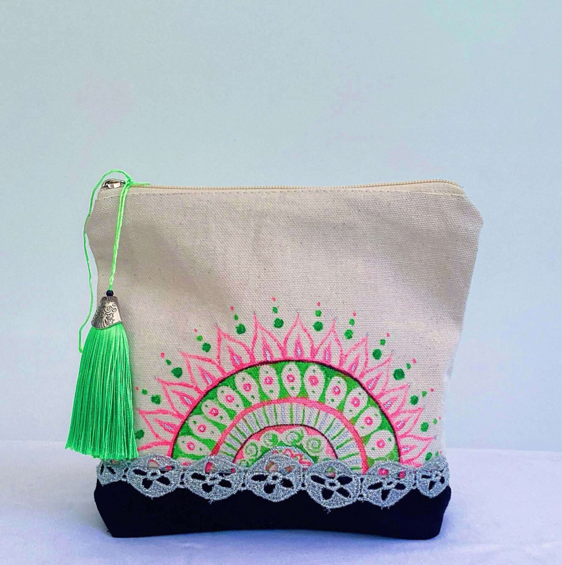 Front view of canvas make-up pouch, black canvas base, with hand painted green and pink half mandala, green tassel and zip.