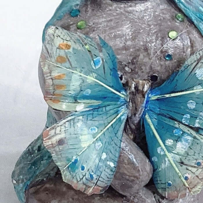 Detail of elemental, brown wash painted figure, holding a feather butterfly.