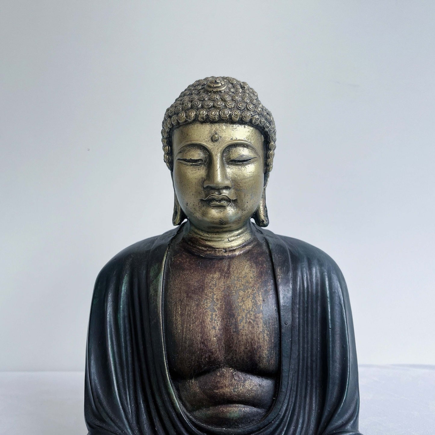 Detail view of buddha, the chest, limbs and head are painted gold, the robes and hair painted a washed ebony.