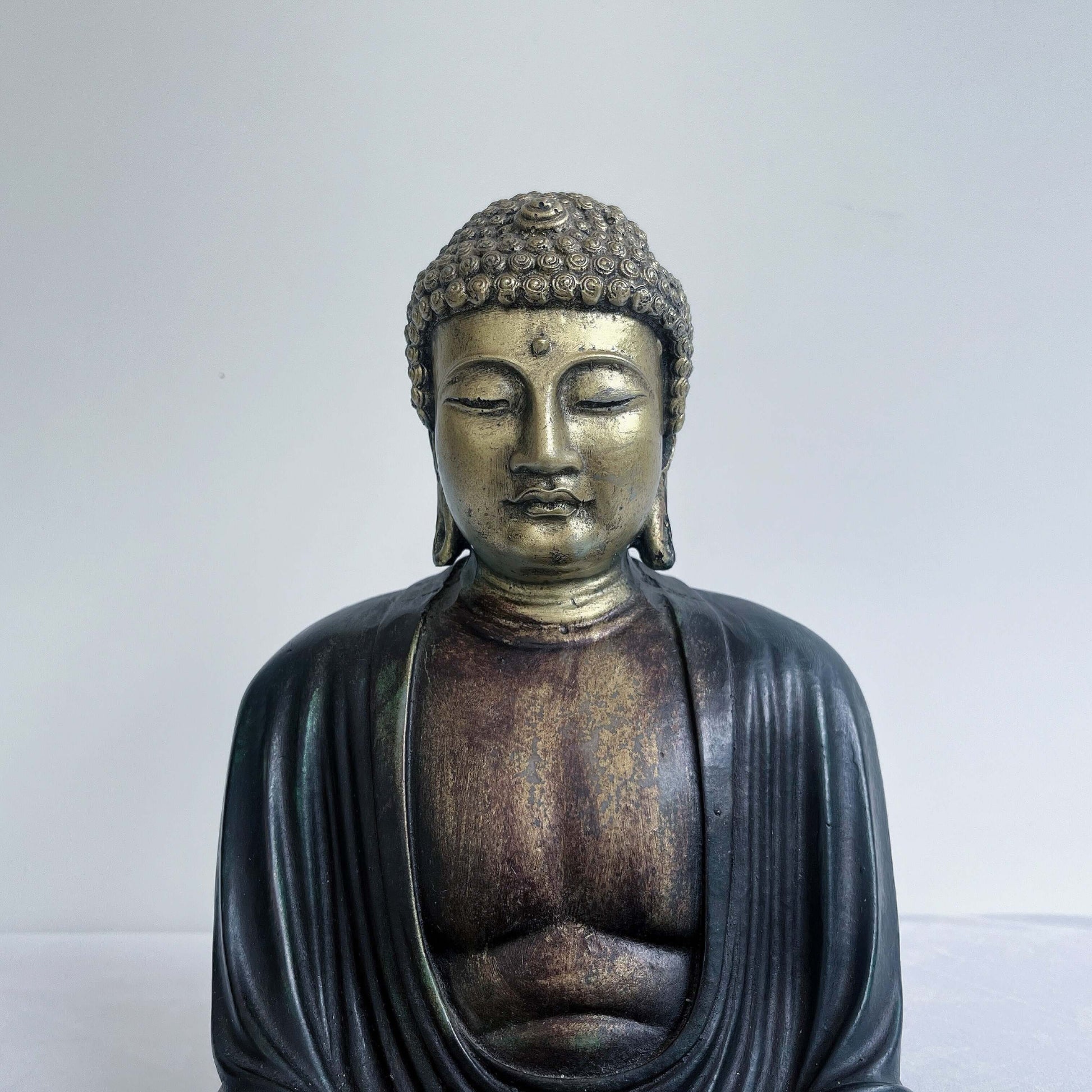 Detail view of buddha, the chest, limbs and head are painted gold, the robes and hair painted a washed ebony.