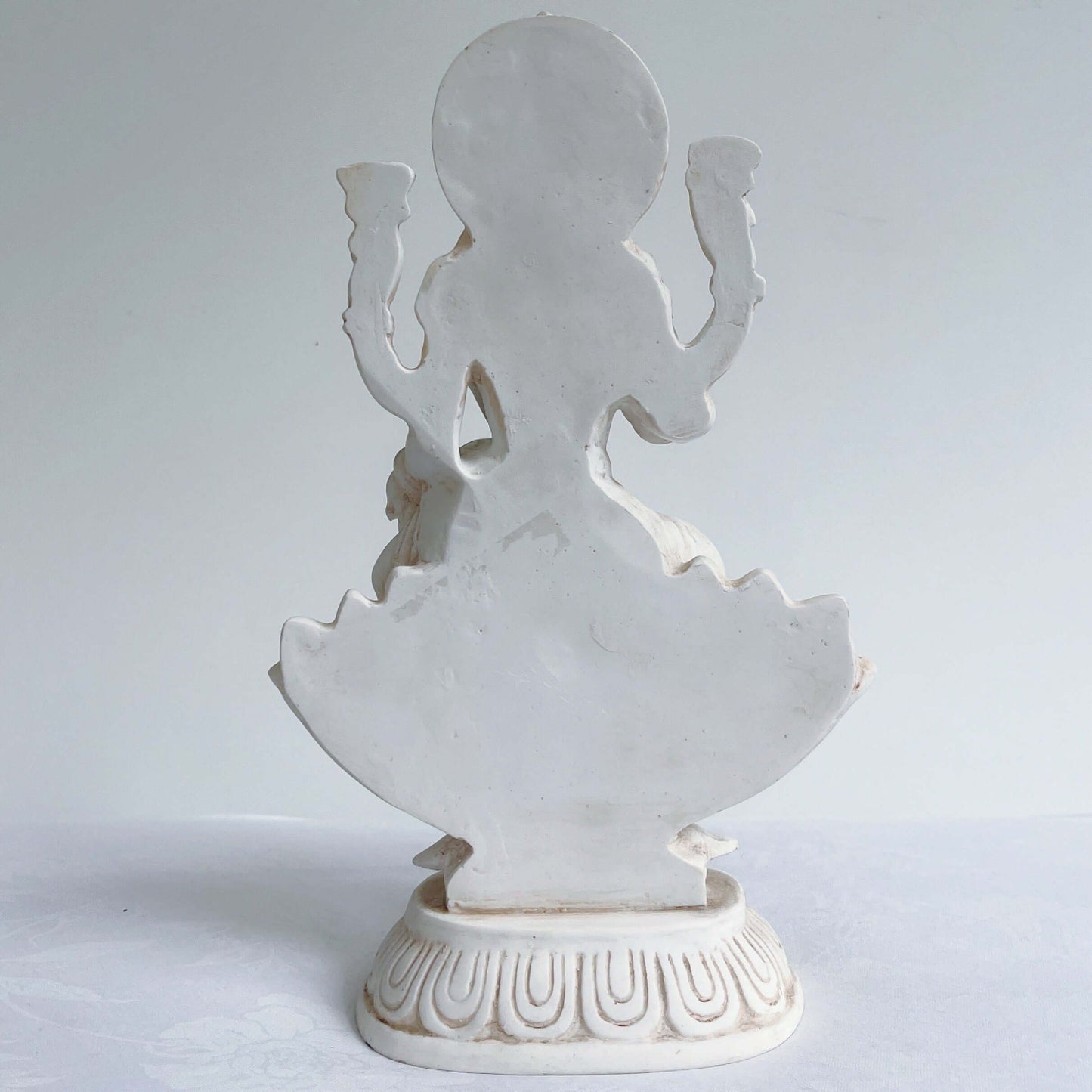 Back view of Lakshmi, natural off white color, resting on lotus flower and pedestal.