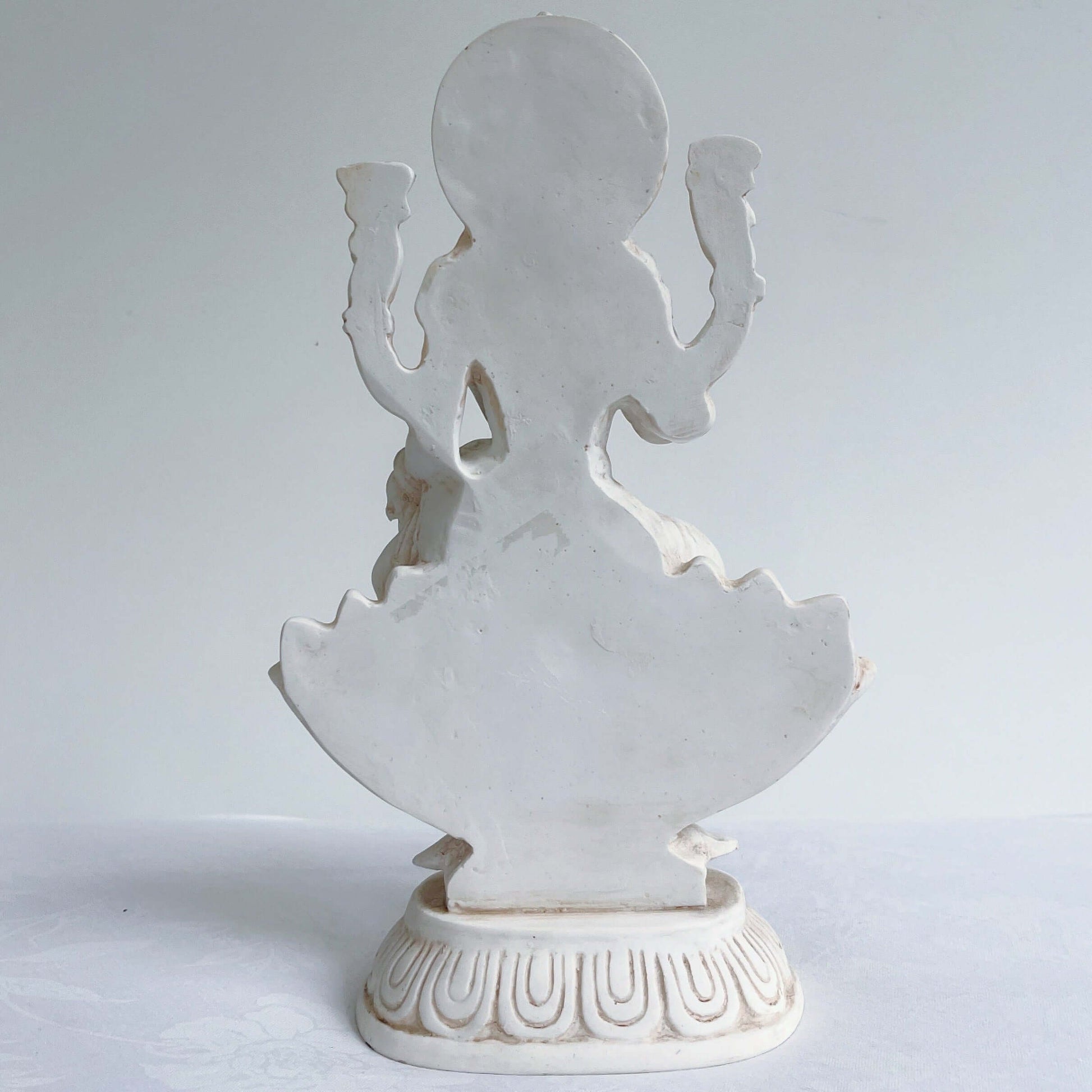 Back view of Lakshmi, natural off white color, resting on lotus flower and pedestal.