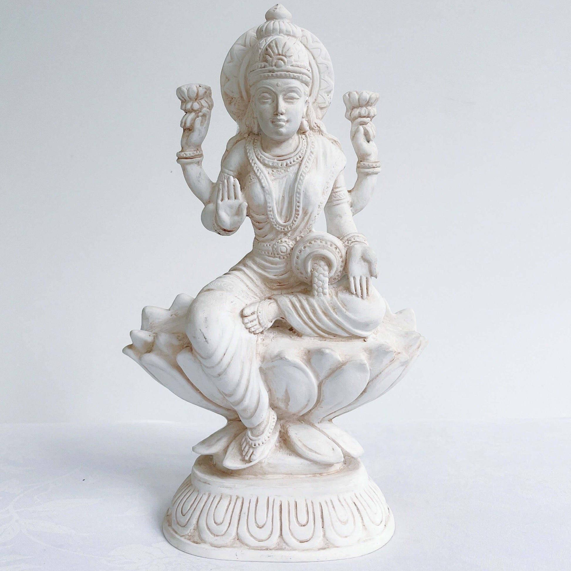 Front view of Lakshmi, natural off white color, resting on lotus flower and pedestal.