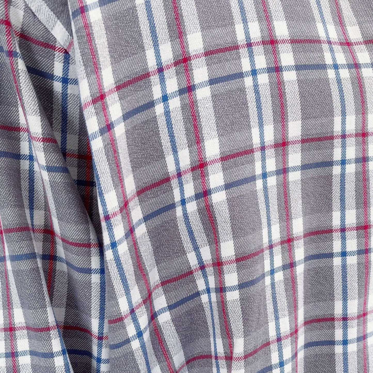 Detail view of the plaid fabric, grey checks with red and blue thin stripes pulling through.