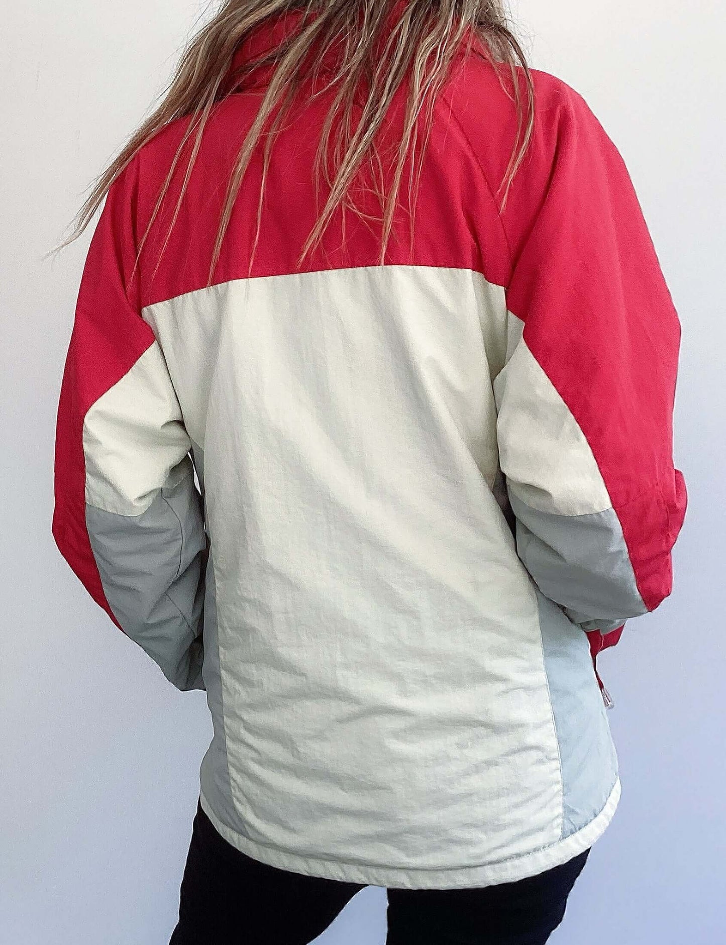 Back view of jacket colors, with red top section and sleeves, below which is all white, and zipped.