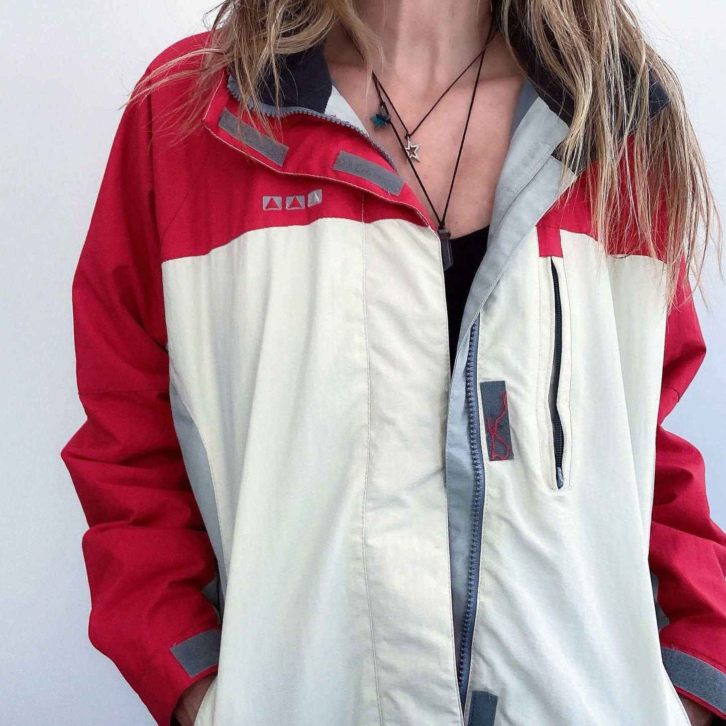 Front view of jacket, with red top section and sleeves, below which is all white, and zipped.