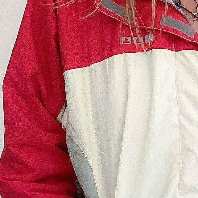 Front detail view of jacket colors, with red top section and sleeves, below which is all white, and zipped.