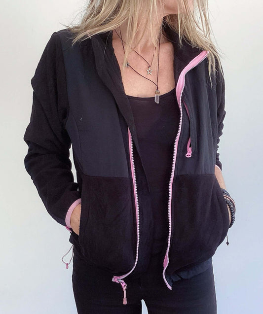 Front view of black zipper jacket, pink trim on the edges, with pockets, hip length.