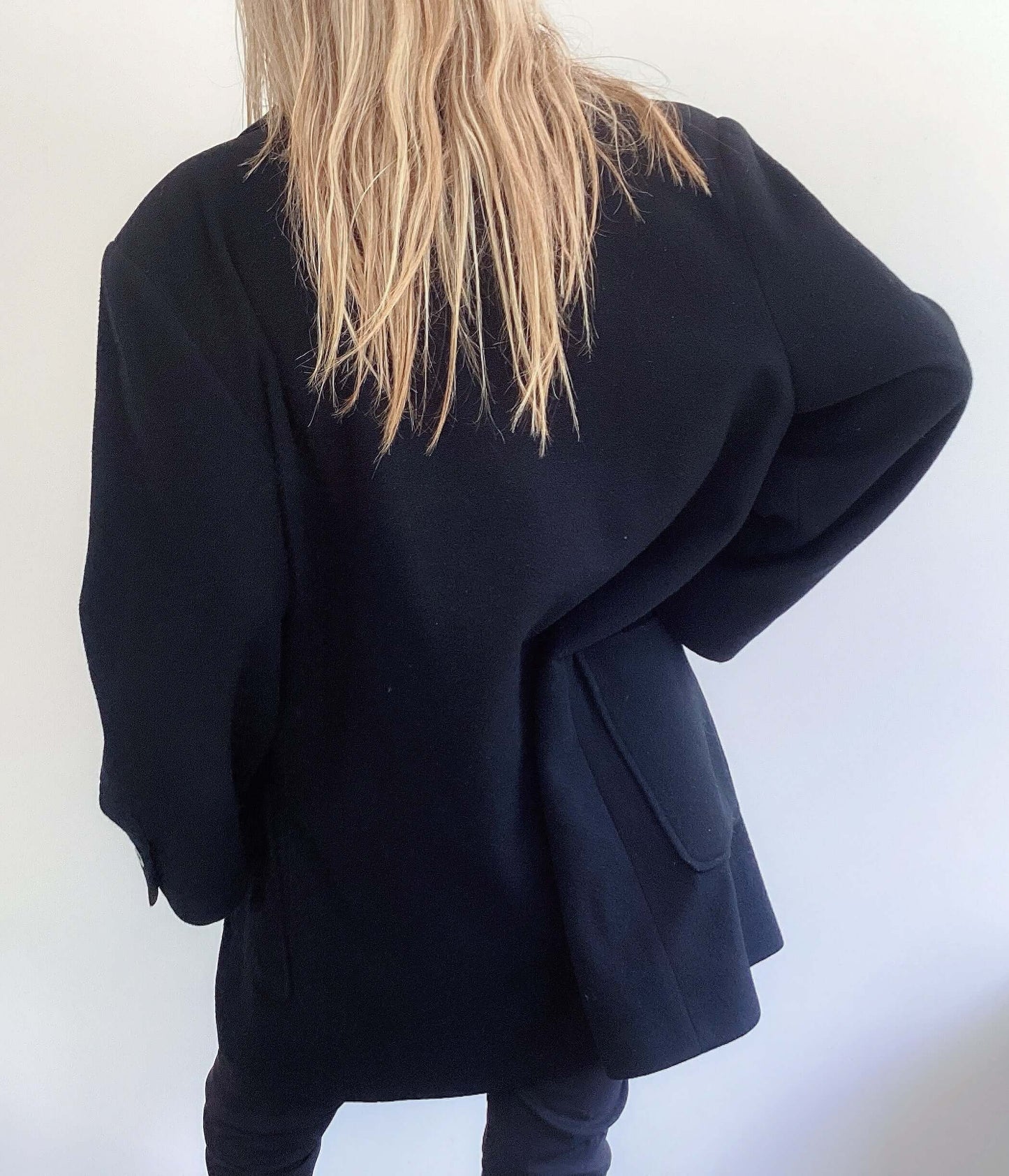 Back view of casual single button coat, two large side pockets, mid thigh length.