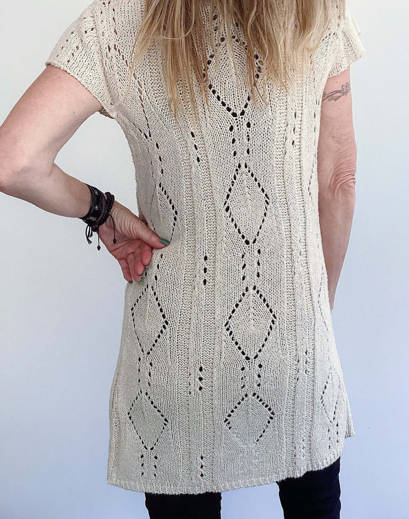 Back view of long beige, celtic rope crocheted jersey, mid thigh length, short sleeves.