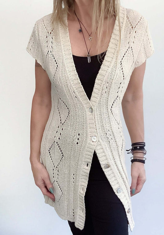 Front view of long beige, celtic rope crocheted jersey, 5 buttons, mid thigh length, short sleeves.