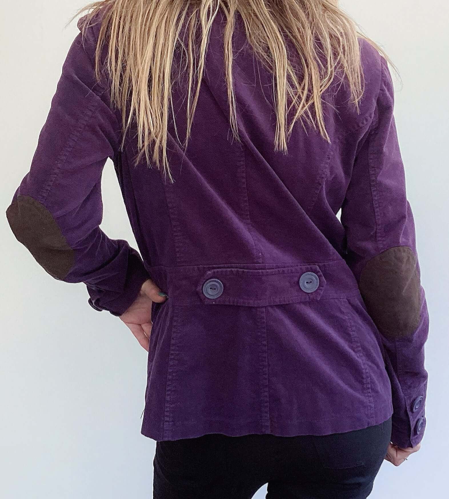 Back view of dark purple single breasted corduroy blazer, brown elbow patch accents, with 2 button back strap.