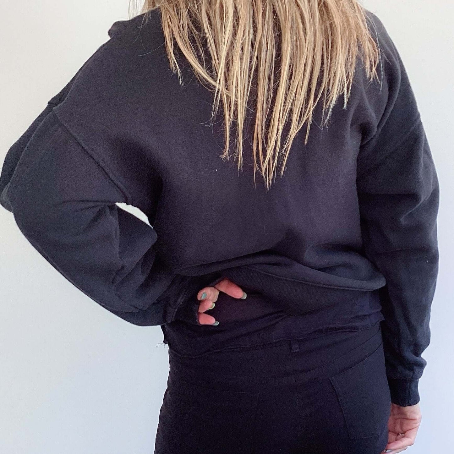 Back view of sweatshirt, plain black, hip length.