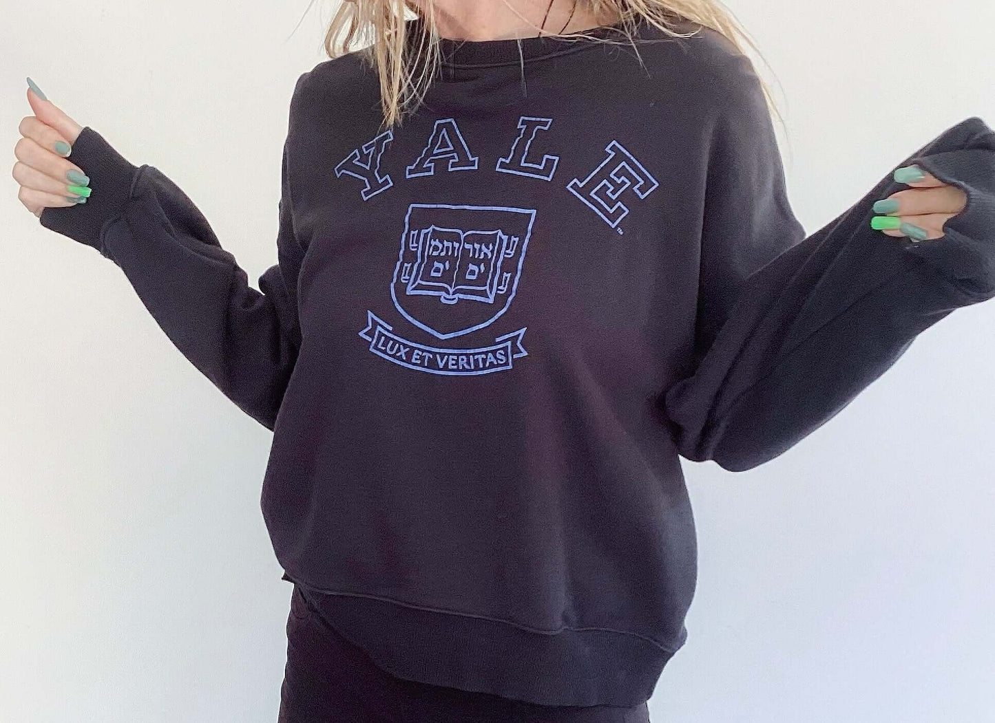 Front view of black sweatshirt, print of yale and lux et veritas in blue, with hebrew writing beneath, hip length.