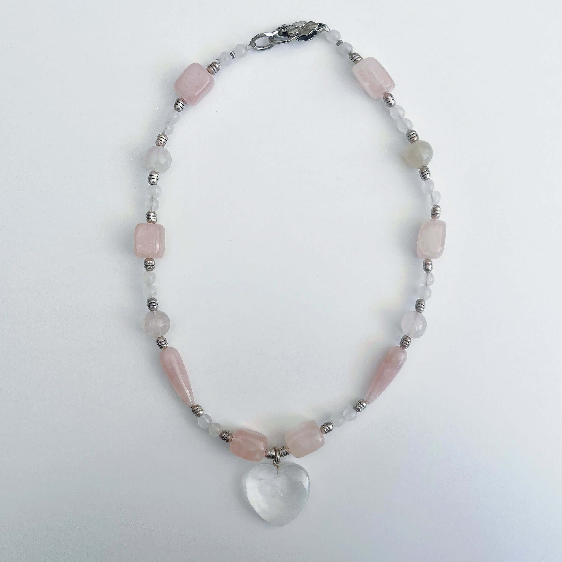 Top view of the Clear Quartz heart pendant, with assorted sized Rose Quartz beads on either side.