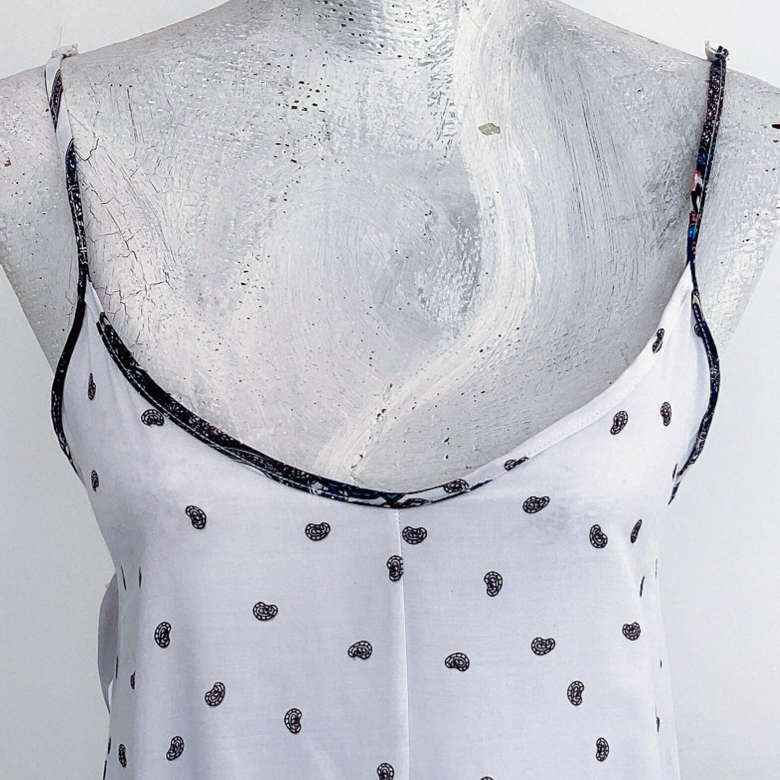 Detail view of white bodice section of dress, delicate black paisley print.