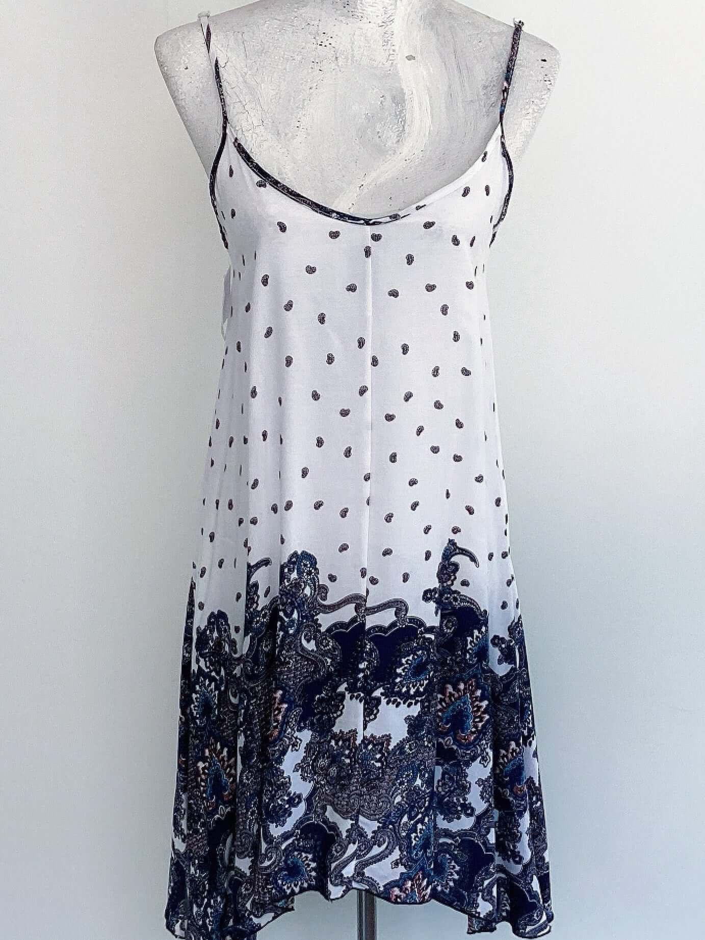 Front view of dress, top half of dress is white with paisley print, bottom half bold navy blue paisley print.