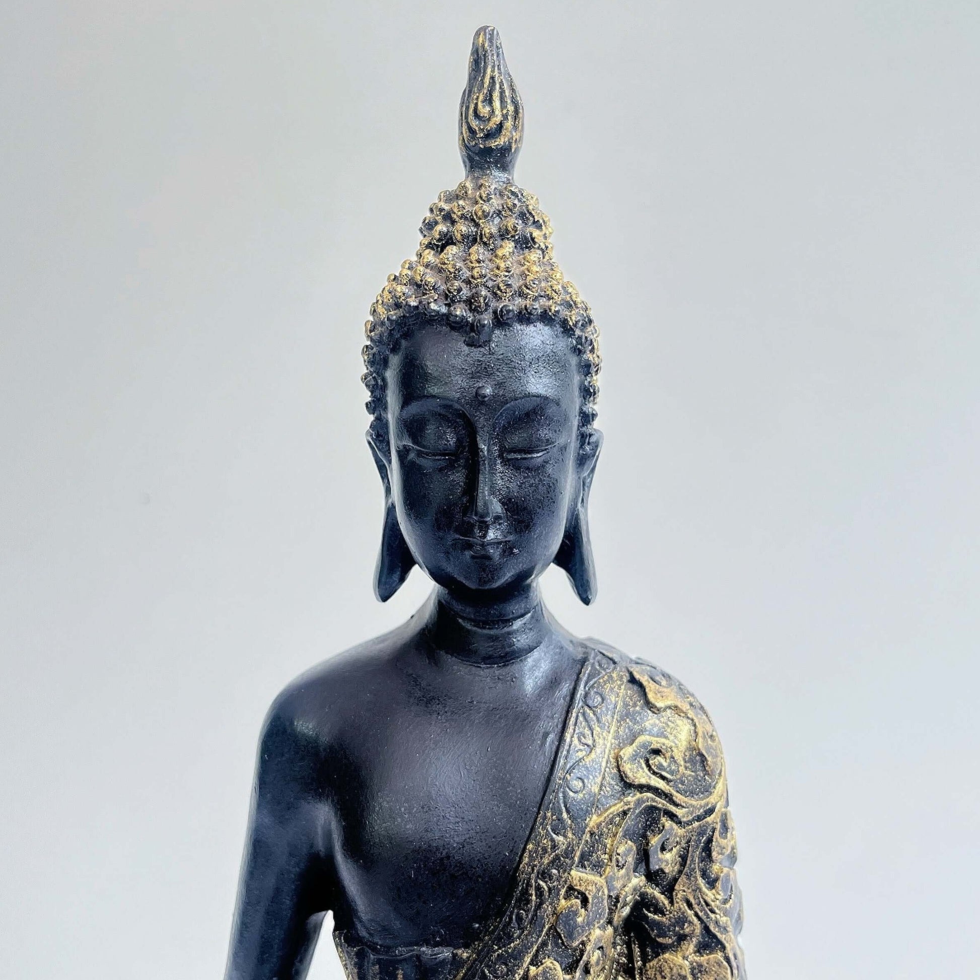 Front detail view of buddha torso, black and gold paint wash, ornate robes, with ushnisha on head.