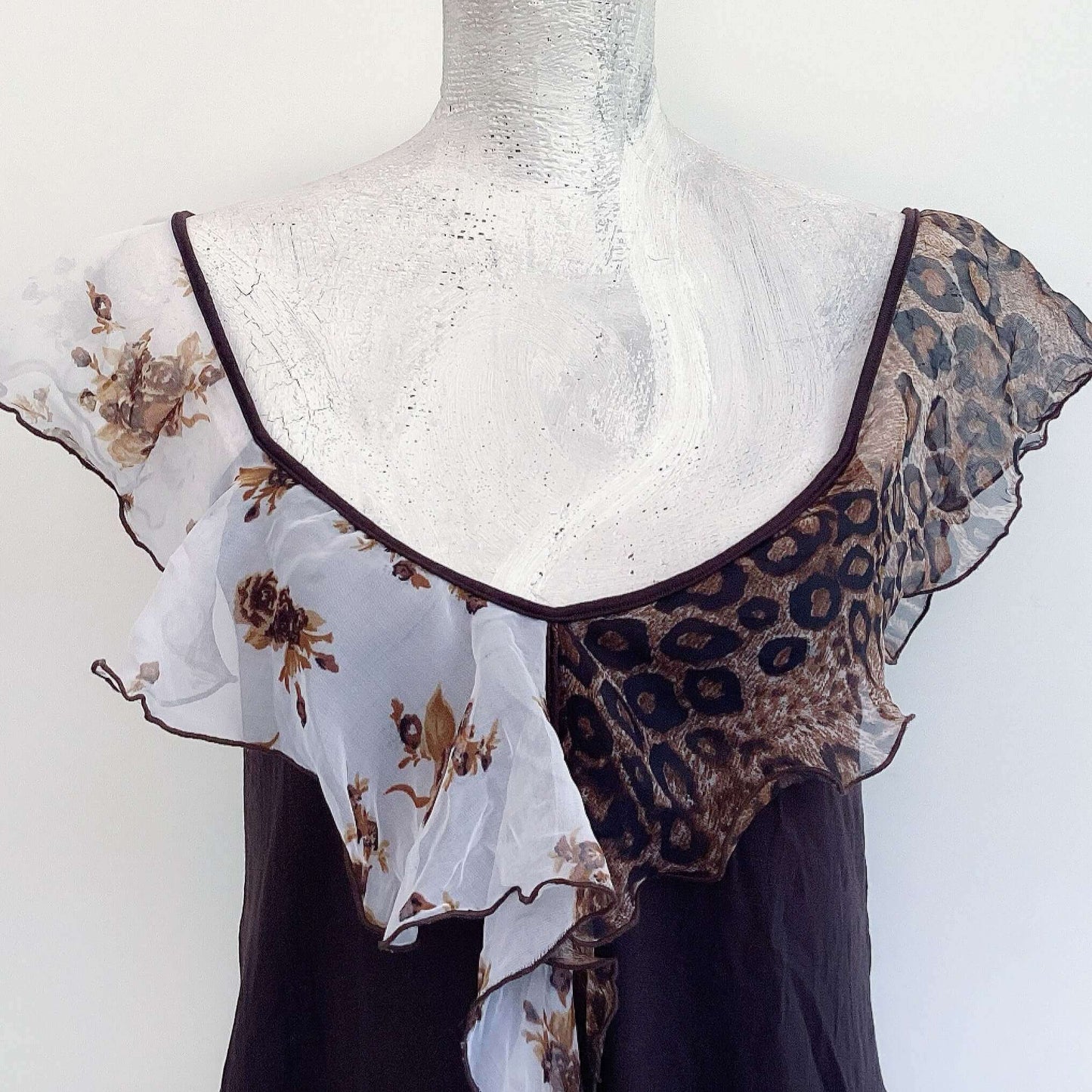 Detail of camisole, contrasting, patterned, wide chiffon frill straps, joining at center bust, flowing down in front.