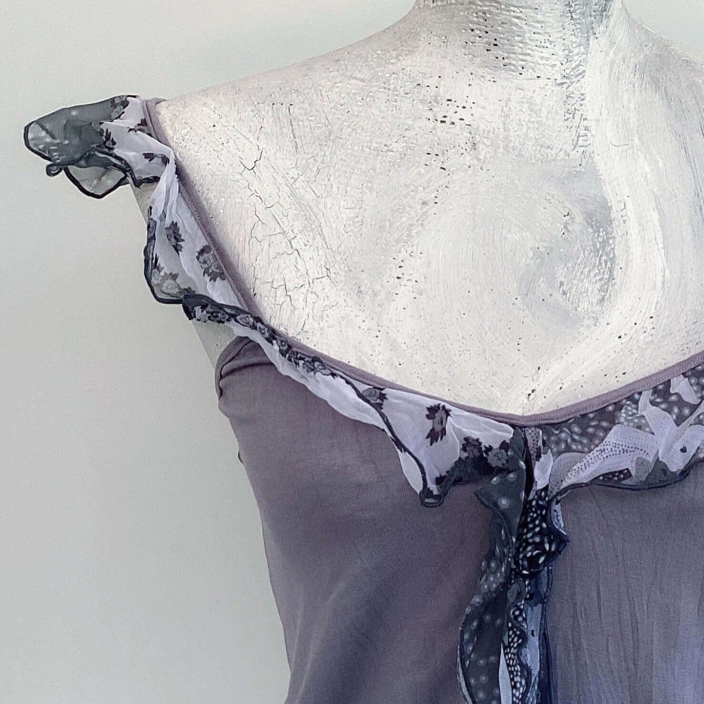 Detail of camisole, contrasting, patterned, wide chiffon frill straps, joining at center bust, flowing down in front.