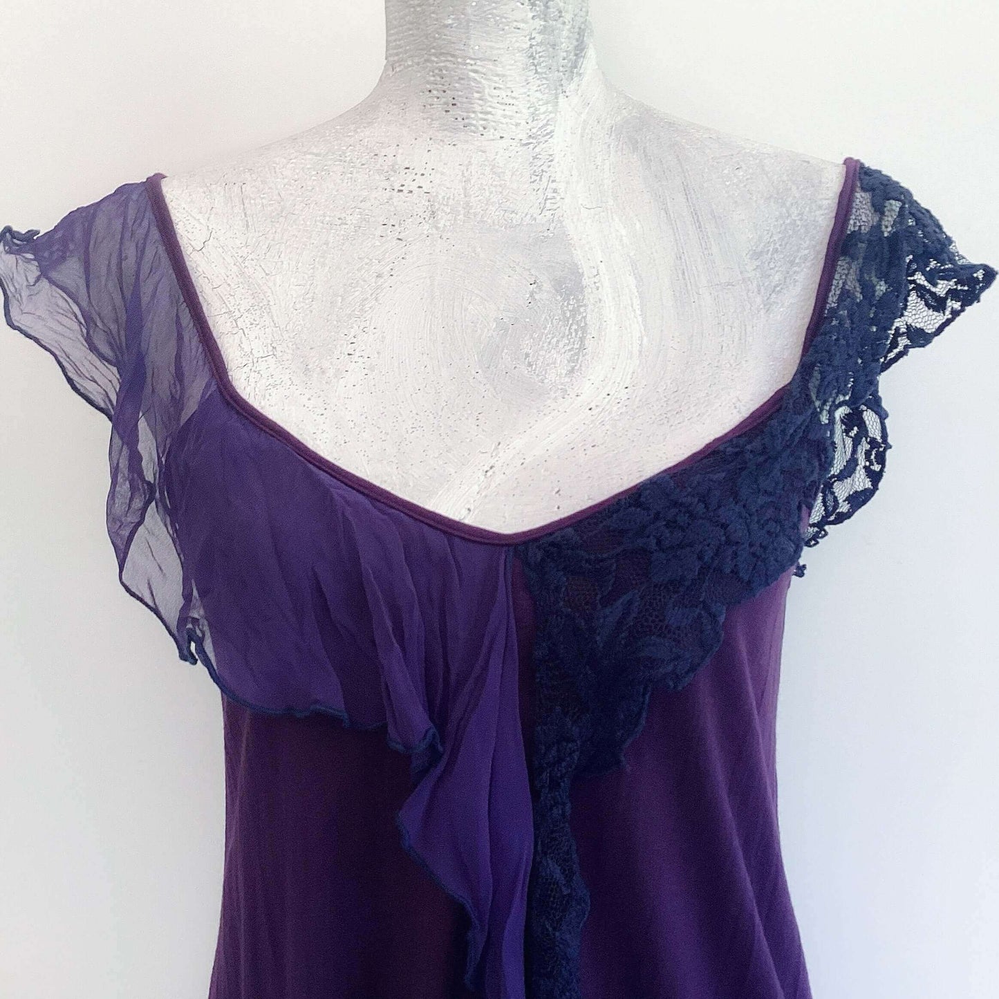 Detail of camisole, contrasting, patterned, wide chiffon frill straps, joining at center bust, flowing down in front.