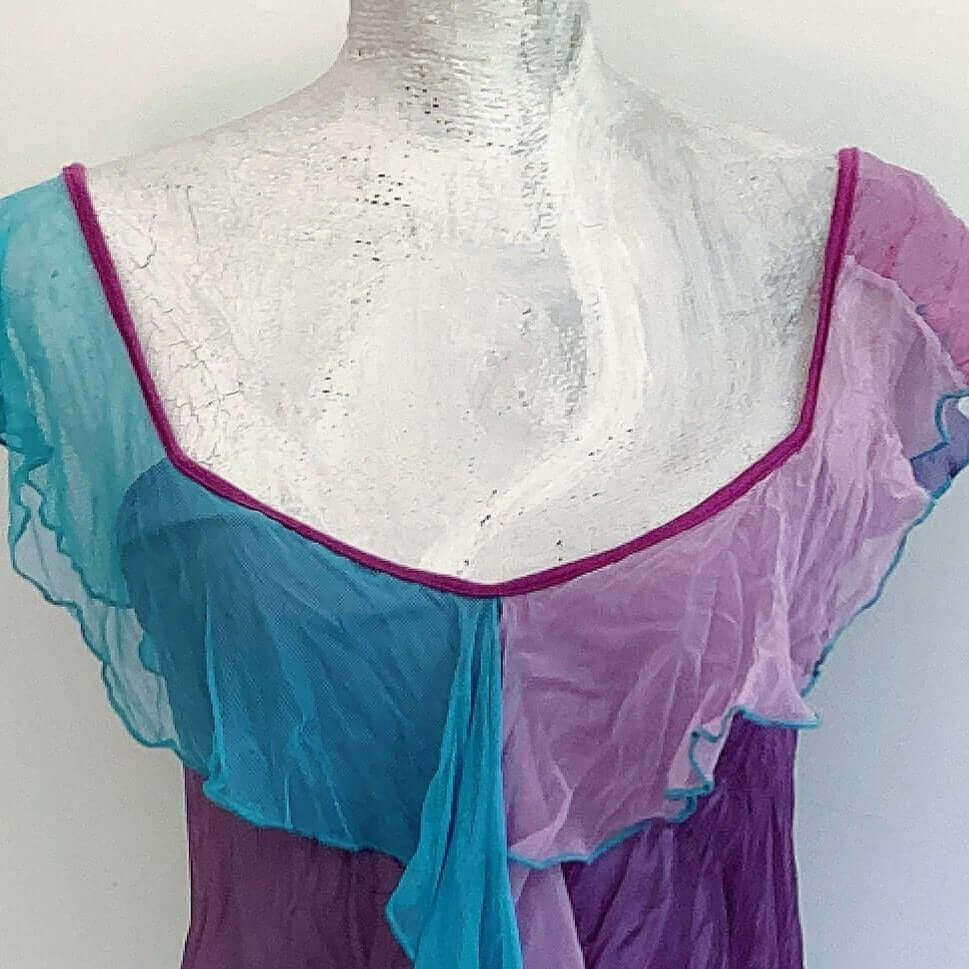 Detail view of camisole, contrasting, patterned, wide chiffon frill straps, joining at center bust, flowing down in front.