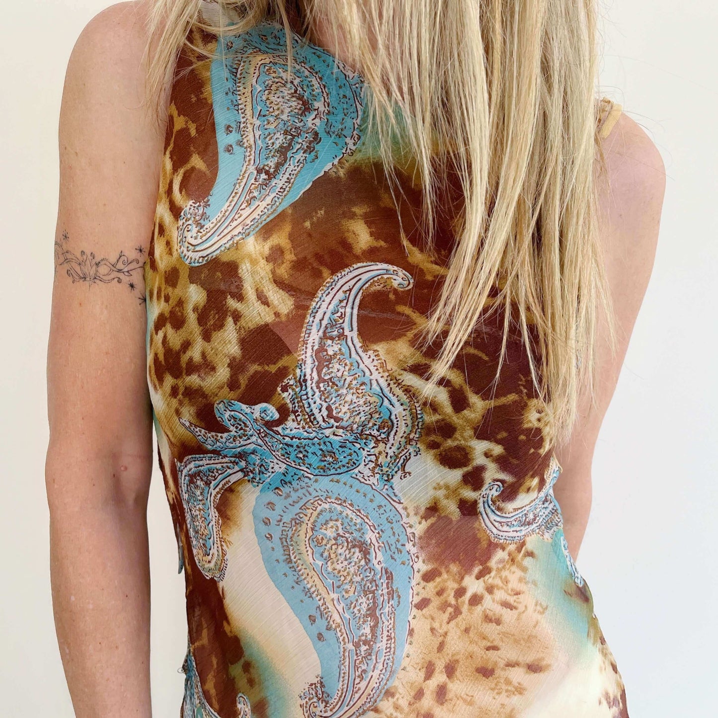 Detail fabric view of asymmetrical off shoulder top, brown and turquoise chiffon, paisley and leopard print.