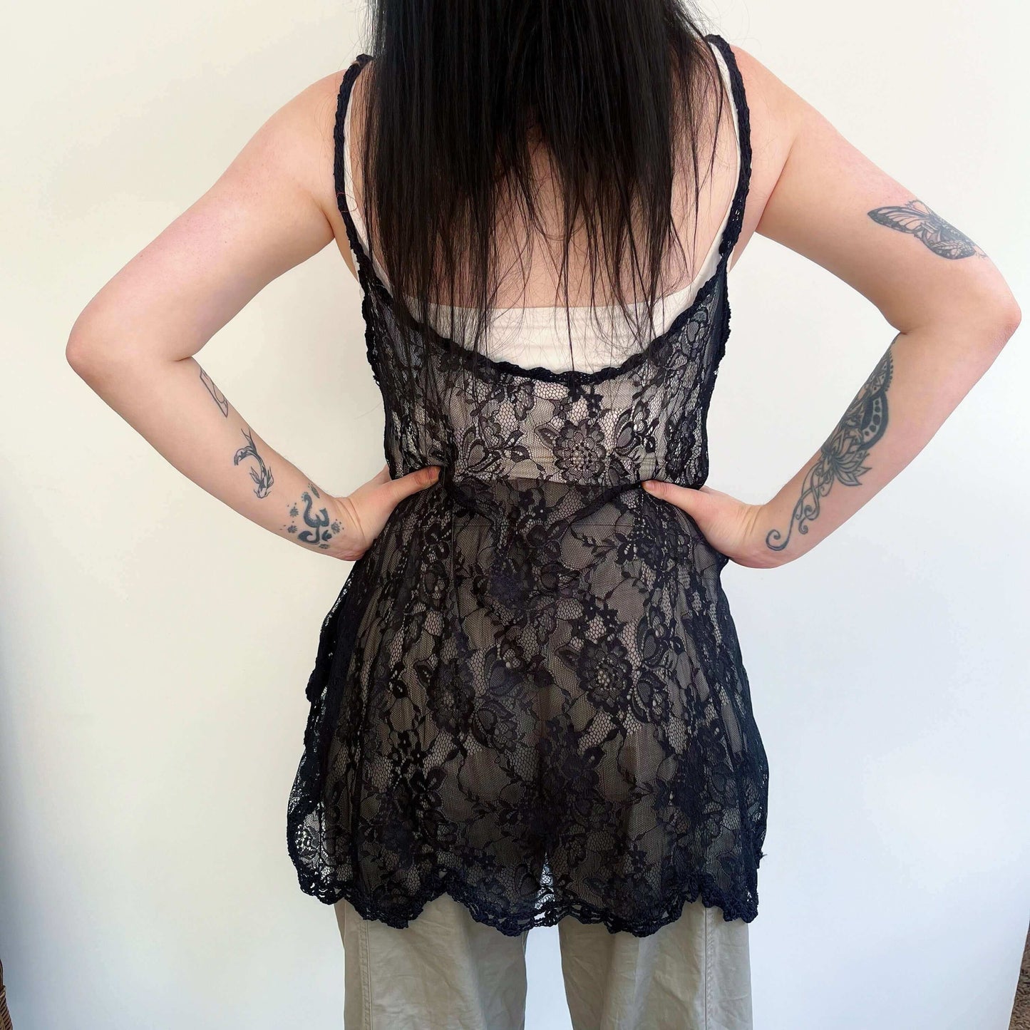 Back view of black lace swing top, wide scalloped hem, with a band of black crochet on the hem and straps.