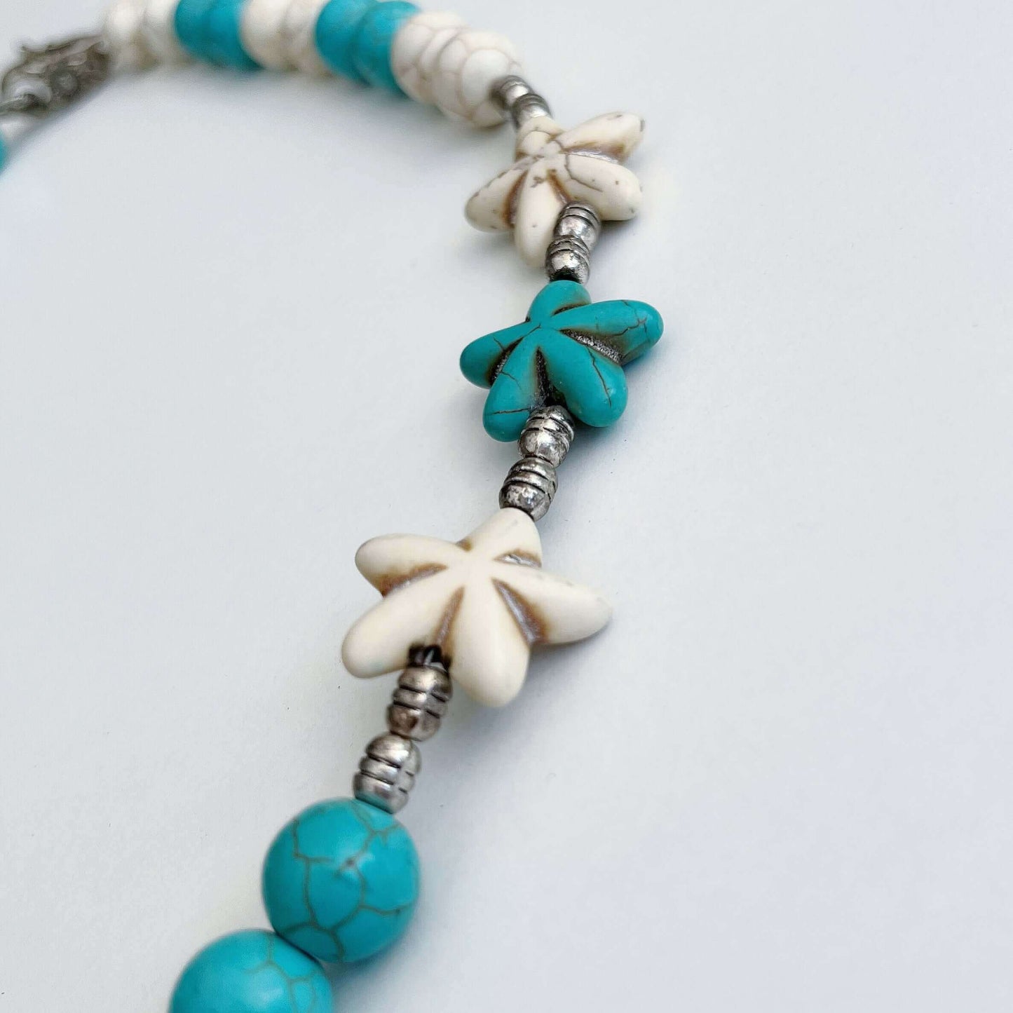 Detail view of the Blue and White Howlite carved daisy beads.