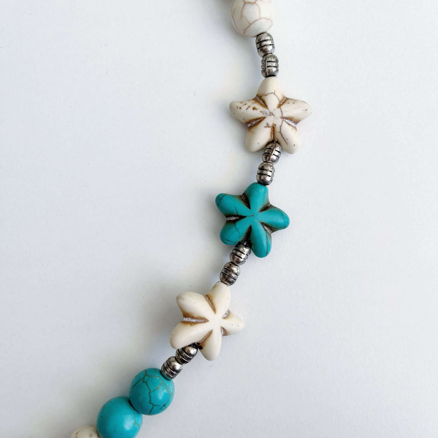 Detail view of the Blue and White Howlite carved daisy beads.