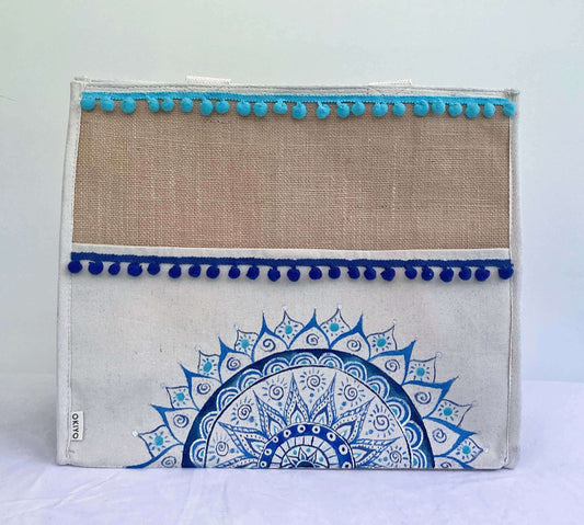 Front of bag, with band of hessian at the top, pompoms stitched across in blue, with painted half mandala on lower part.